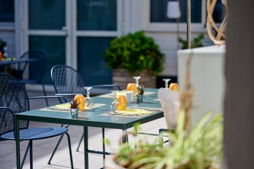 a green table with chairs and drinks on a patio at The Originals Boutique, Hôtel La Colonne de Bronze, Saint-Valéry-sur-Somme in Saint-Valery-sur-Somme