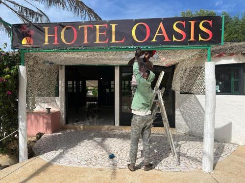 un homme tenant un enfant sous un panneau indiquant l'oasis de l'hôtel dans l'établissement Eco-Lodge Hotel Oasis Fishing, à Saint-Louis