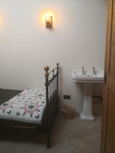 a bathroom with a bed and a sink and a lamp at The Workshop, in 18th century Lothersdale Mill, BD20 8EN in Keighley