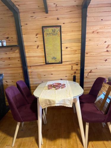 a dining room with a table and two purple chairs at Lake View Bungalow Close to Airport in Arnavutköy