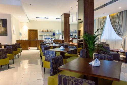 un restaurante con mesas, sillas y una barra en The Seven Hotel, en Manama