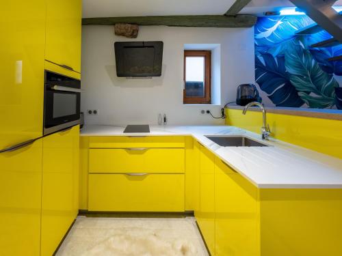 een gele keuken met een wastafel en een magnetron bij Le Pinot Gris in Riquewihr