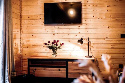 una pared de madera con una mesa con un jarrón de flores en Dychnij Se en Szczyrk