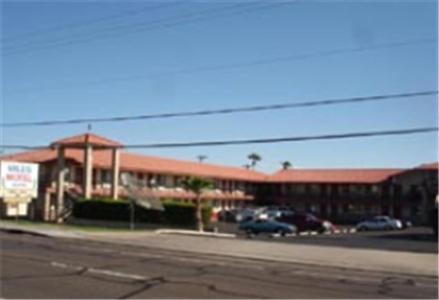 ein großes Gebäude mit Autos auf einem Parkplatz in der Unterkunft Miles Motel in Mesa