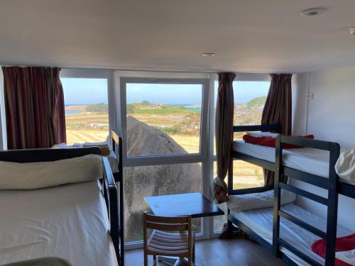 a bedroom with bunk beds and a view of the ocean at Auberge Granit Rose - Hébergement partagé en Auberge de Jeunesse - Vue sur mer - Dortoir mixte & Camping in Trébeurden