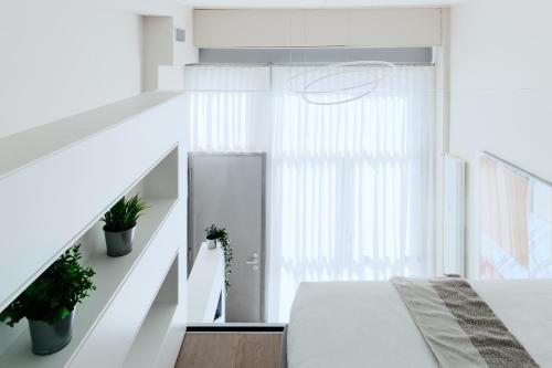 a white bedroom with a bed and a staircase at Touch&Go - via Gaetano Previati 38, Milano in Milan