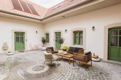 an outdoor patio with green doors and chairs at Dunakavics XIII Apartman in Szentendre