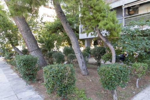 a row of trees and bushes in front of a building at Peristeri 2 BD flat next to metro Agios Antonios in Athens