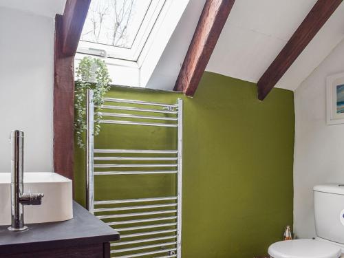 a bathroom with green walls and a skylight at The Stables in Fowey
