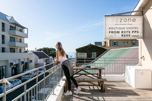 a woman standing on the balcony of a hotel at Zzzone Boutique Hostel in Hermanus
