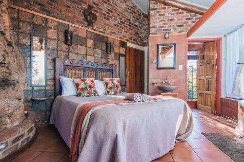 - une chambre avec un grand lit dans un mur en briques dans l'établissement Thabela Thabeng, à Parys