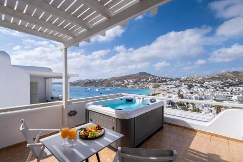 a balcony with a hot tub and a table with a bowl of fruit at Deliades Hotel in Ornos