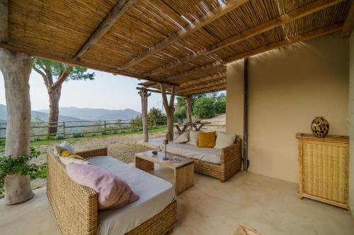 a porch with wicker chairs and a table and a view at Villa Elicriso Charme e Nature - Goelba in Portoferraio