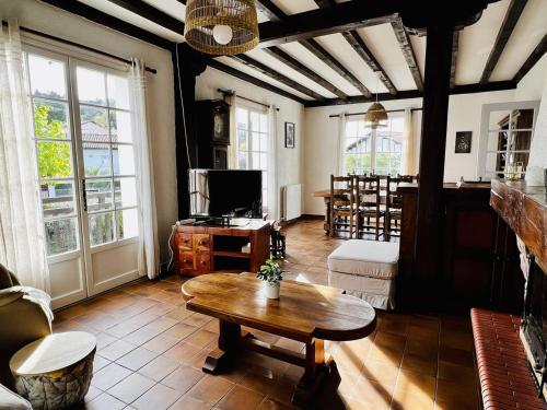 un salon avec une table et une télévision dans l'établissement Maison T4 à Cambo-les-Bains: 5 couchages, jardin arboré, balcon, cheminée, animaux acceptés, Wi-Fi fibre - FR-1-495-114, à Cambo-les-Bains