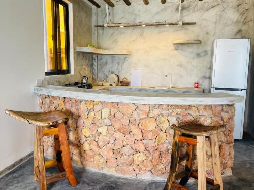 a kitchen with a stone counter and two stools at Chunga Changa in Matemwe