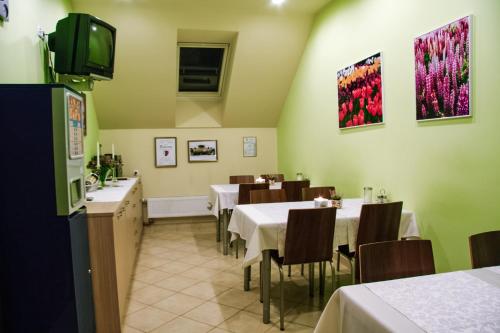 a dining room with tables and chairs and a tv at Homestay Sreš in Mlaka pri Kranju