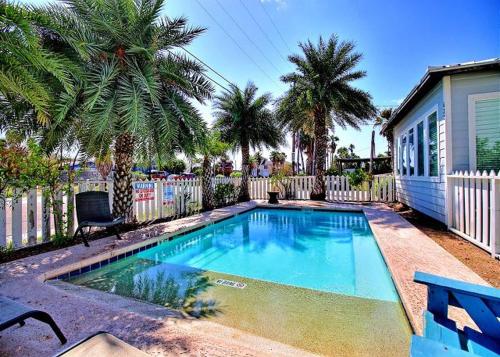 a swimming pool in front of a house with palm trees at Beach Club 1 in Port Aransas