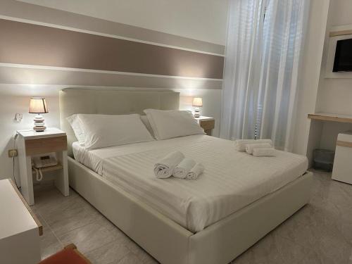 1 dormitorio con 1 cama blanca y 2 toallas en Porto Cesareo Hotel, en Porto Cesareo