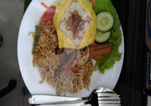 un piatto di cibo con spaghetti e verdure su un tavolo di Omnea Hotel - Syariah a Bengkulu