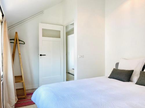 a white bedroom with a white bed and a door at Zeehuis Zuidzande ZZ3 in Zuidzande