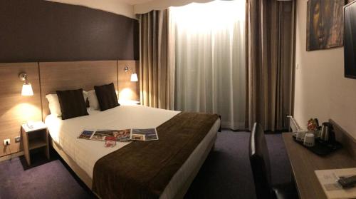 a hotel room with a bed with a magazine on it at The Originals City, Hôtel Villancourt, Grenoble Sud in Le Pont-de-Claix
