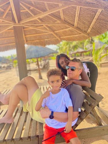 a family sitting on a bench on the beach at Eco-Lodge Hotel Oasis Fishing in Saint-Louis