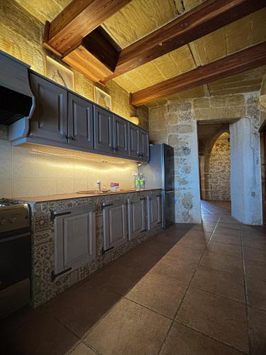 a kitchen with black cabinets and a tile floor at 300y/o Farmhouse BLUE LAGOON VIEWS /AC/POOL QALA in Qala