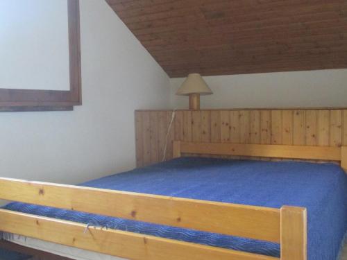 Un dormitorio con una gran cama de madera con sábanas azules en Appartement 3 pièces 6 couchages à Risoul, calme et proche des pistes - FR-1-330-310, en Risoul