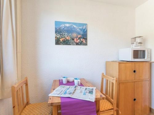 - une table à manger avec un four micro-ondes et une table avec un journal dans l'établissement Studio cosy pour 2 à La Salle-les-Alpes, proche pistes et commerces - FR-1-330F-162, à La Salle Les Alpes