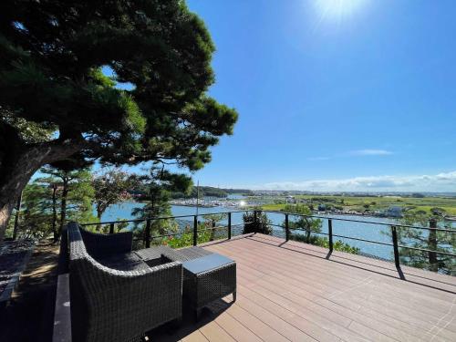 a bench on a deck with a view of the water at Hitachinaka Villa DAN - ひたちなか 暖 - in Hitachinaka