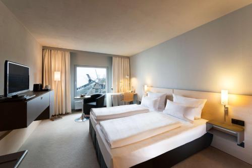ein Hotelzimmer mit einem großen Bett und einem TV in der Unterkunft Atlantic Hotel Universum in Bremen