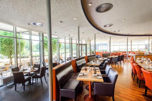 um restaurante com mesas, cadeiras e janelas em Atlantic Hotel Universum em Bremen