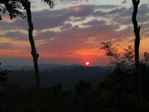 a sunset with the sun setting in the distance at The Periaheights in Periya