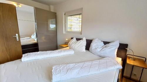 a bedroom with two beds with white pillows at MONA Haus KMB Seeblick Appartement am Ossiacher See mit direktem Seezugang, Hallenbad in Bodensdorf