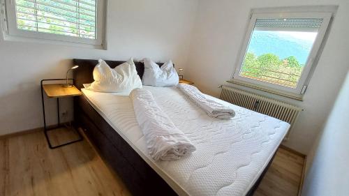 a bedroom with a bed with white sheets and a window at MONA Haus KMB Seeblick Appartement am Ossiacher See mit direktem Seezugang, Hallenbad in Bodensdorf