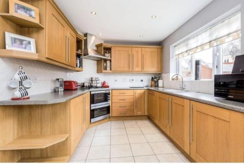 a kitchen with wooden cabinets and a large window at SPACIOUS DETACHED 5 Bedroom4 Bathroom WIFI Parking in Newcastle under Lyme