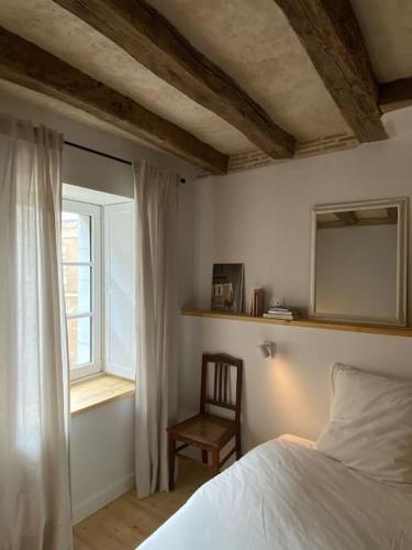 a bedroom with a bed and a chair and a window at La petite maison de Savennières in Savennières