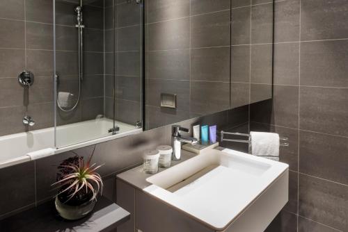 een badkamer met een witte wastafel en een douche bij SANA Berlin Residence in Berlijn