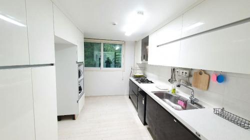 a white kitchen with a sink and a stove at Gamseong House in Sejong