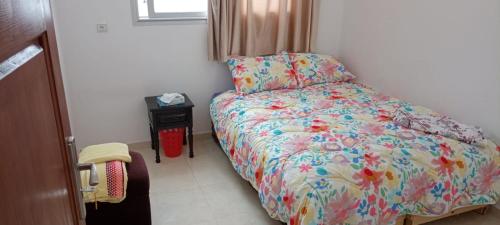 een kleine slaapkamer met een bed met een kleurrijk dekbed bij Dar Ba Brahim in Rabat