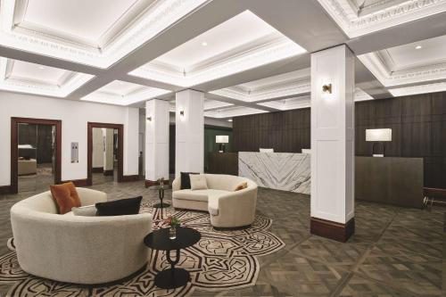 a lobby with two couches and chairs and tables at Rendezvous Hotel Melbourne in Melbourne