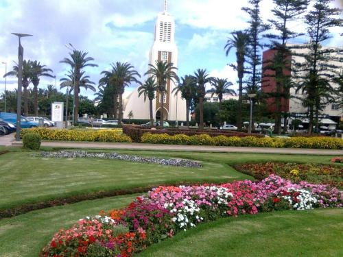 a building with a clock tower and flowers in a park at A 200m de la Plage, du Haut Standing au coeur du Parc in Mohammedia