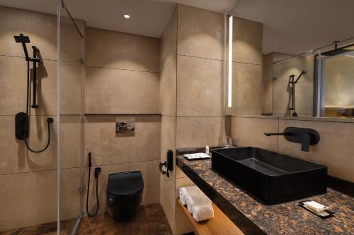 a bathroom with a black sink and a shower at INFINITEA CENTRIC DHARAMSHALA in Dharamshala