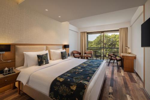 a bedroom with a large bed and a large window at INFINITEA CENTRIC DHARAMSHALA in Dharamshala