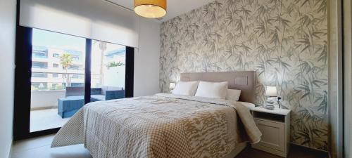 een slaapkamer met een bed en een muur met plantenbehang bij Luxury apartment in Flamenca Village/Orihuela Costa in Orihuela-Costa