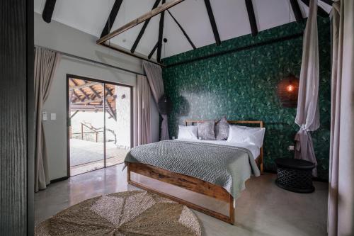 a bedroom with a bed and a green wall at Mukumbura Lodge Bilene in Vila Praia Do Bilene