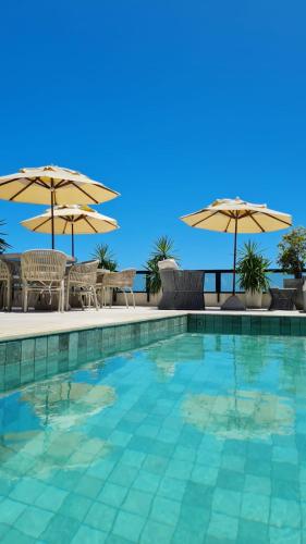 a swimming pool with chairs and umbrellas at Carppa Hotel in Fortaleza
