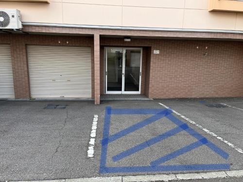 un estacionamiento con líneas azules frente a un edificio en ＡｋＢ33 Room-2, en Teine