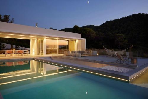 a house with a swimming pool in front of it at OHLIVE Beach Villa Skiathos in Kechria