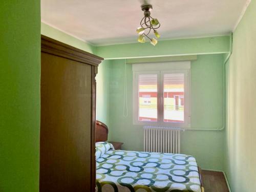 um quarto verde com uma cama e uma janela em Habitación doble en apartamento de 3 habitaciones em Salamanca